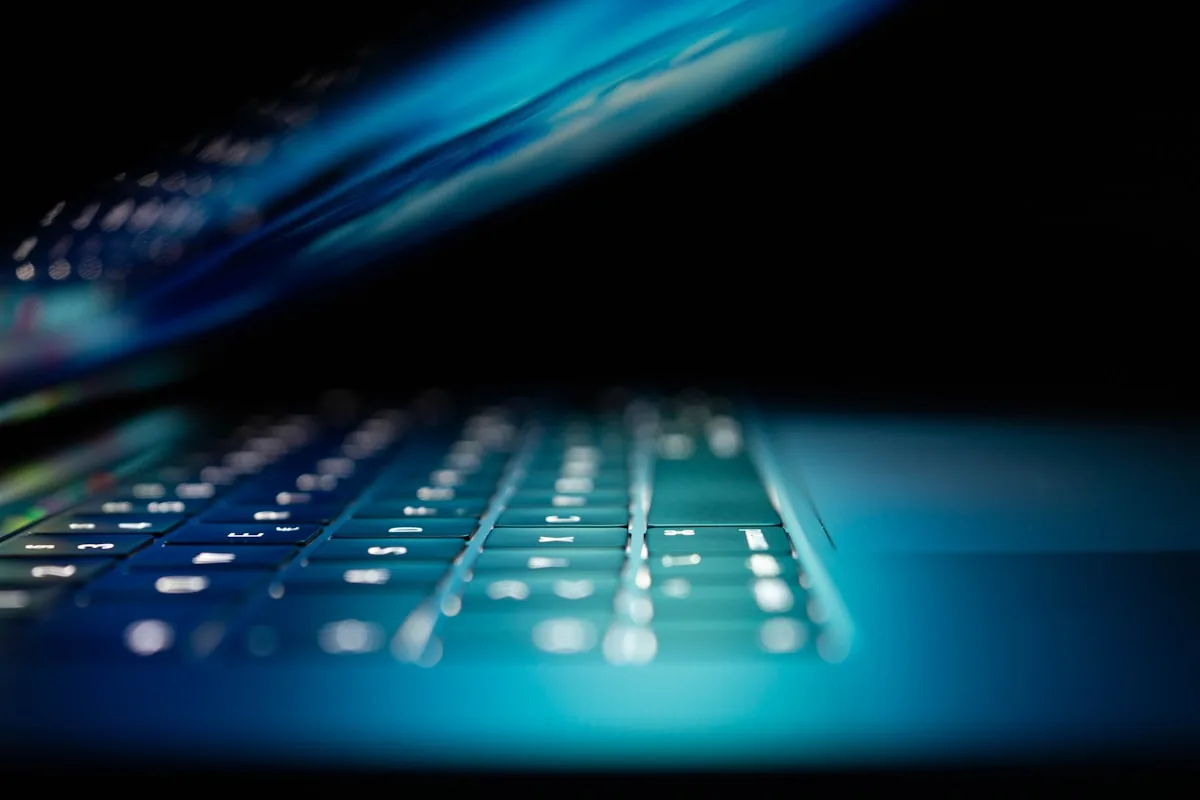Laptop keyboard illuminated by a cybersecurity monitoring dashboard
